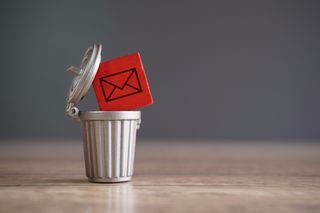 Closeup image of wooden cube with mail icon inside trash can.