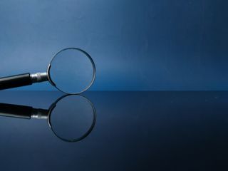 Reflection magnifying glass on a black acrylic board with blue background