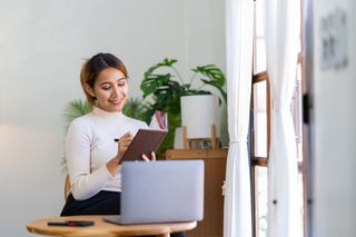 Portrait of a beautiful and attractive businesswoman smiling and taking notes. Guidelines as one of the best tips for writing blog posts