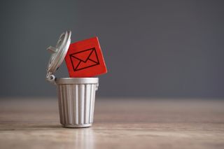 Closeup image of wooden cube with mail icon inside trash can.